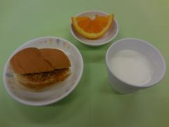 ミートサンドと牛乳と果物の写真