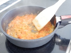 湯むきし1センチ角に切ったトマトと薄切りのたまねぎを鍋にオリーブ油を熱し炒める写真